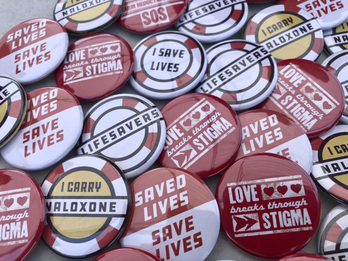 Buttons are displayed at a tent during a health event Saturday, June 26, 2021, in Charleston, W.Va. Volunteers at the tent passed out the buttons along with free doses of naloxone, a drug that reverses the effects of an opioid overdose by helping the person breathe again. Activists at the event called on the city of Charleston to declare a public health emergency for new HIV cases and prescription drug overdoses. (AP Photo/John Raby)
