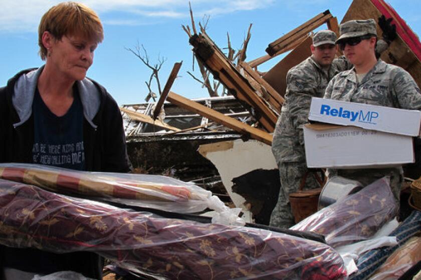 Josephine Owings, 62, who survived a direct hit by a tornado on her rented home in Moore, Okla., Monday afternoon, gets help recovering belongings Tuesday. Owings returned to salvage items from her home-based seamstress business.