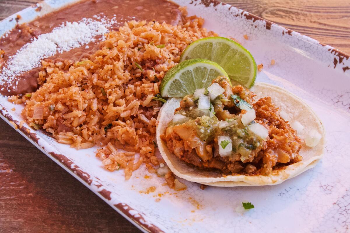 A cauliflower taco on a plate with limes, rice and beans from Rancho del Zocalo in Frontierland.