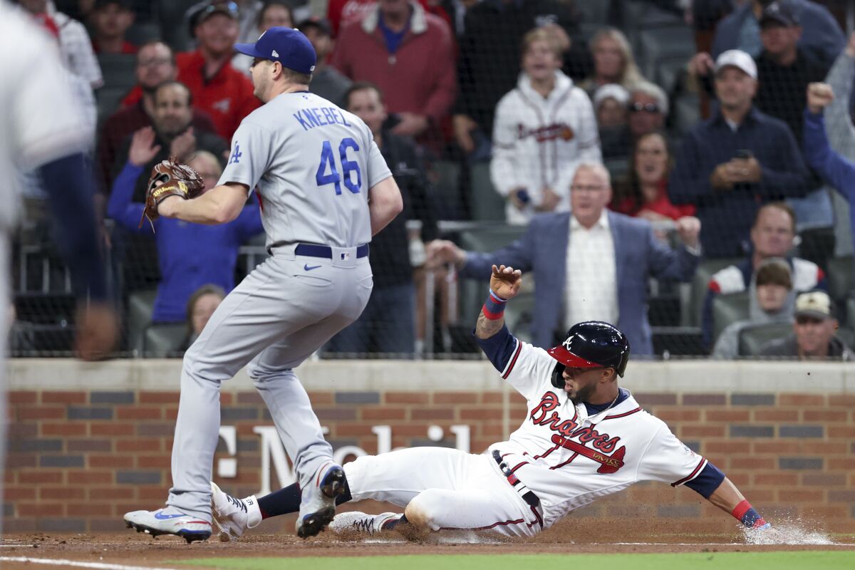 Atlanta's Eddie Rosario slides into home after a wild pitch by the Dodgers' Corey Knebel, left, during the first inning.