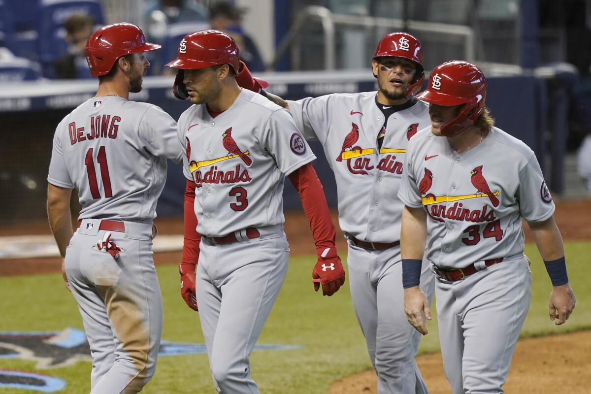 St. Louis Cardinals' John Nogowski (34), Yadier Molina (4) and Paul DeJong (11) congratulate Dylan Carlson (3) after Carlson hit a grand slam in the ninth inning of a baseball game against the Miami Marlins, Wednesday, April 7, 2021, in Miami. The Cardinals defeated the Marlins 7-0. (AP Photo/Marta Lavandier)