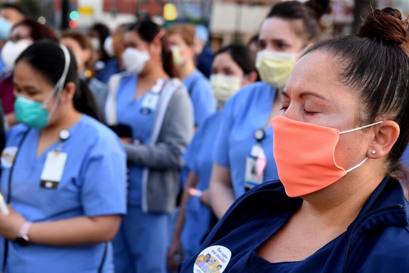 LOS ANGELES, CALIFORNIA MAY 6, 2020-Monique Hernandez, a registered nurse for Riverside Community Hospital, attends a candlelight vigil for nurse Celia Marcos outside Hollywood Presbyterian Medical Center in Los Angeles Wednesday. Marco died from the coronavirus. (Wally Skalij/Los Angeles Times)