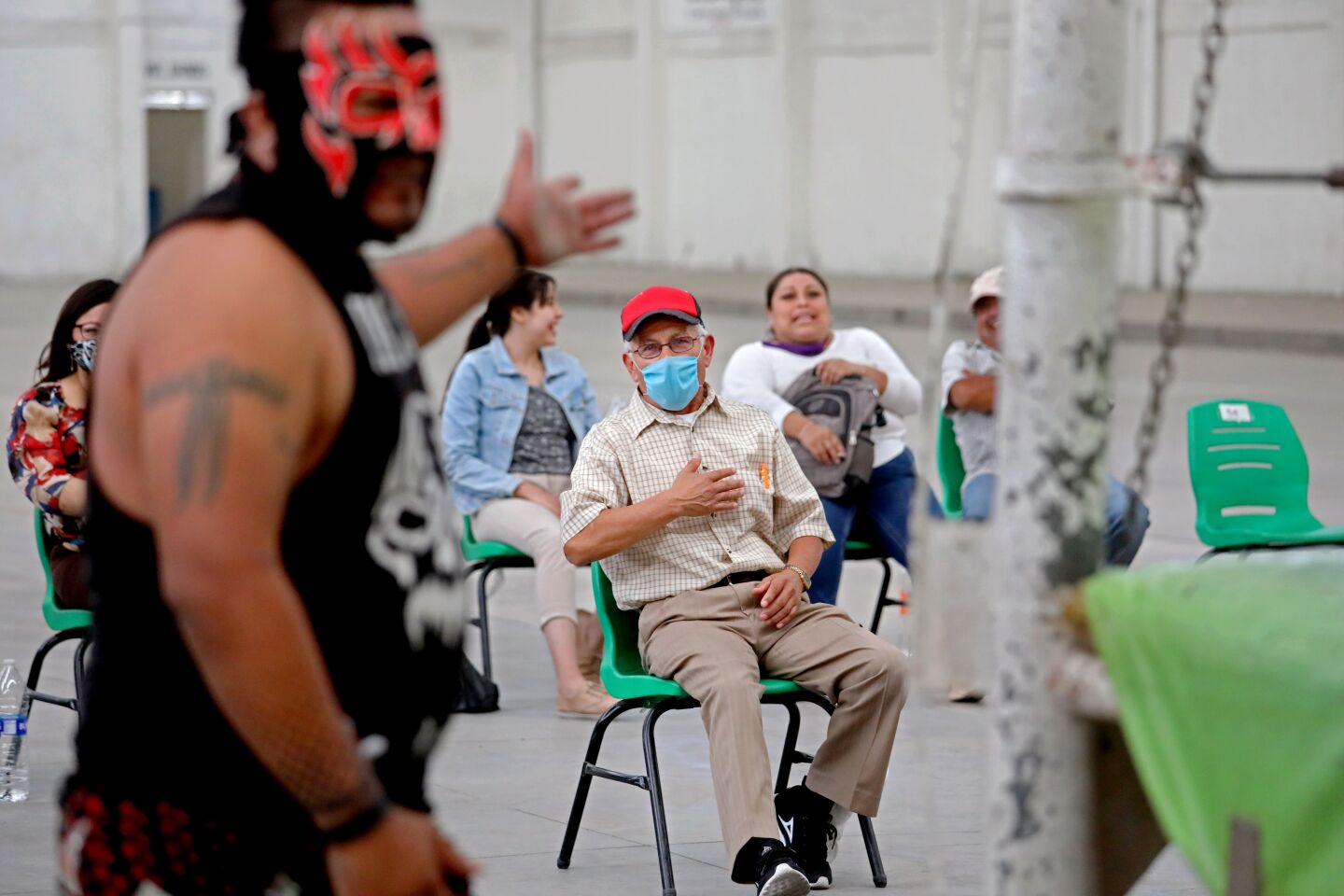 Wrestler Maldad, left, banters with fan Pascual Galindo, center, at a lucha libre event Aug. 23.