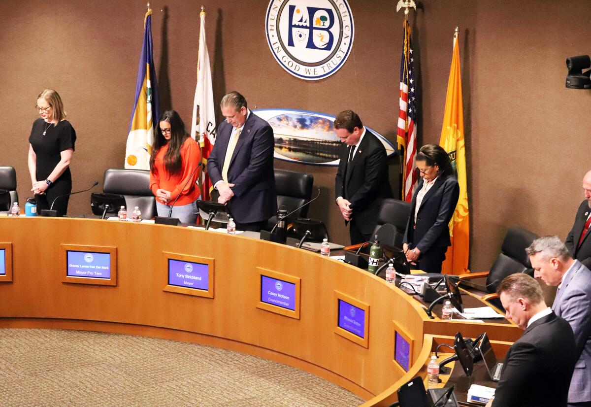 The Huntington Beach City Council members bow their heads in prayer during the invocation.