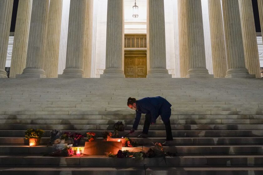 People lay flowers and light candies outside the Supreme Court Friday, Sept. 18, 2020, in Washington, after the Supreme Court announced that Supreme Court Justice Ruth Bader Ginsburg died of metastatic pancreatic cancer at age 87. (AP Photo/Alex Brandon)