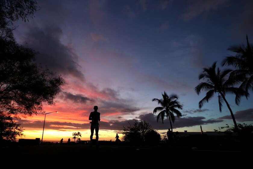 A silhouette of a man on the island of Hawaii at dusk or dawn.