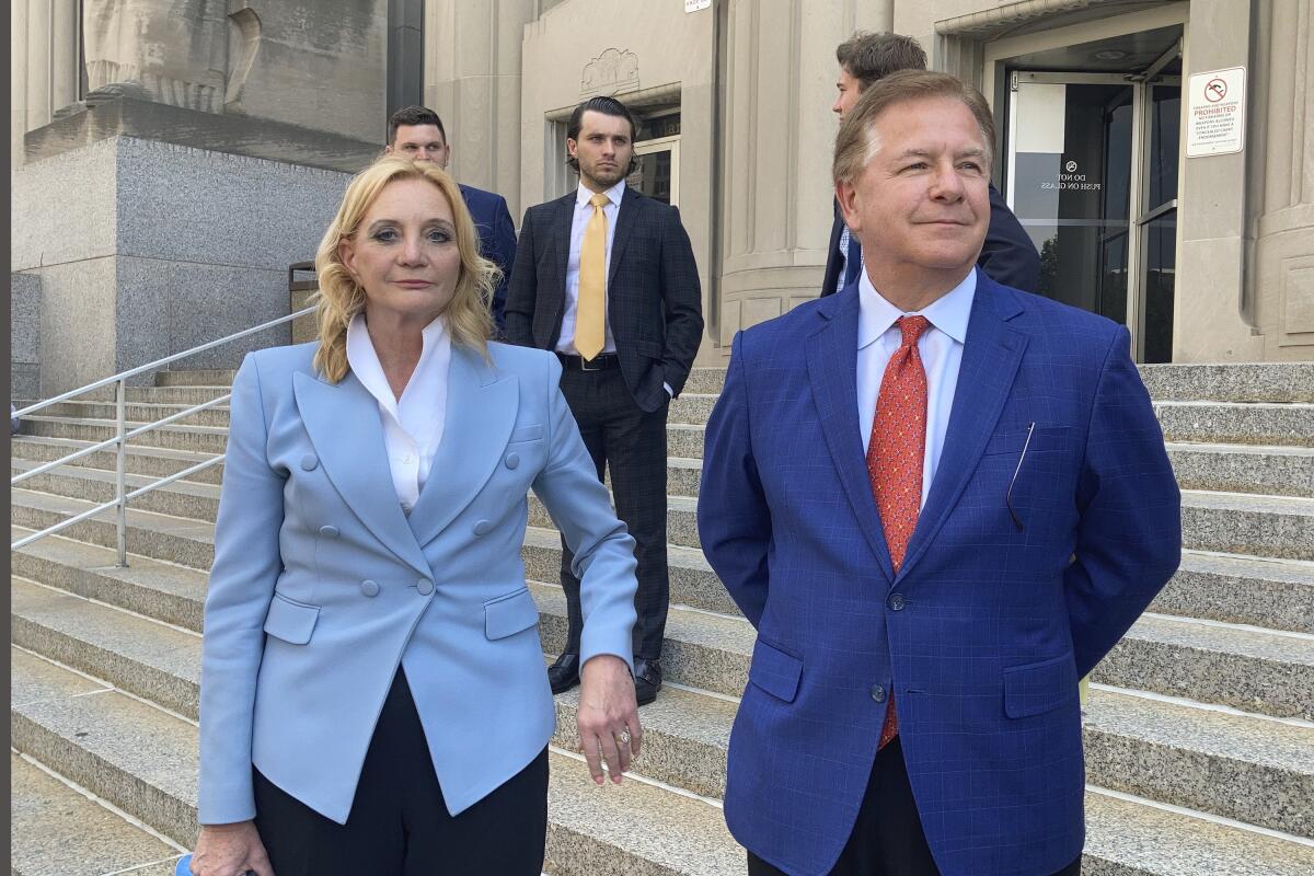 Two people stand on the steps of an official-looking building.