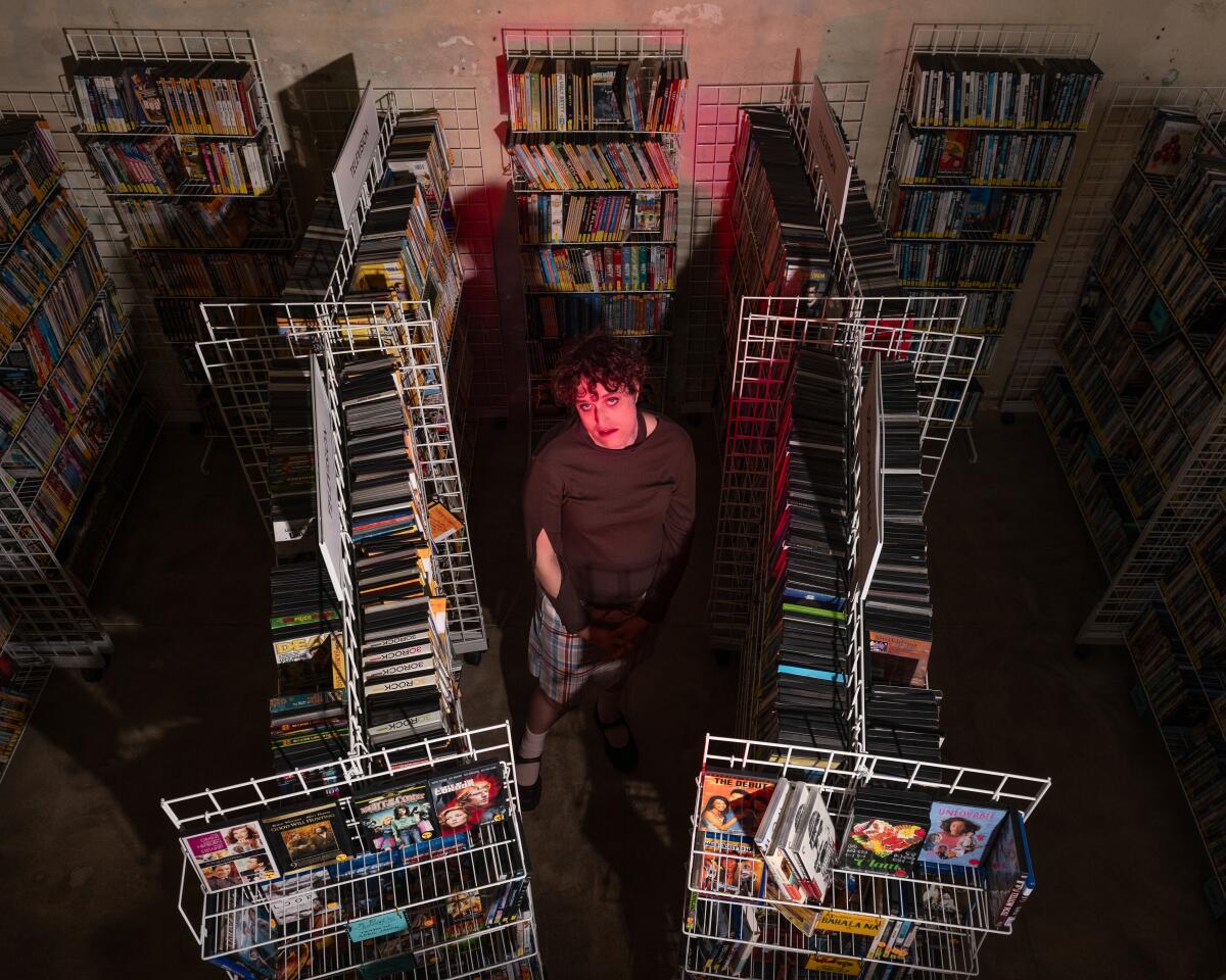 A filmmaker stands among rows of thousands of DVDs and Blu-rays.
