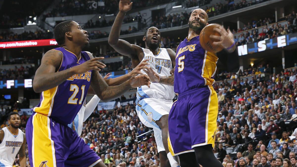 Lakers forward Carlos Boozer, right, pulls in a rebound in front of Denver Nuggets forward J.J. Hickson, center, and Lakers forward Ed Davis during the fourth quarter of the Lakers' 111-103 win on Dec. 30.