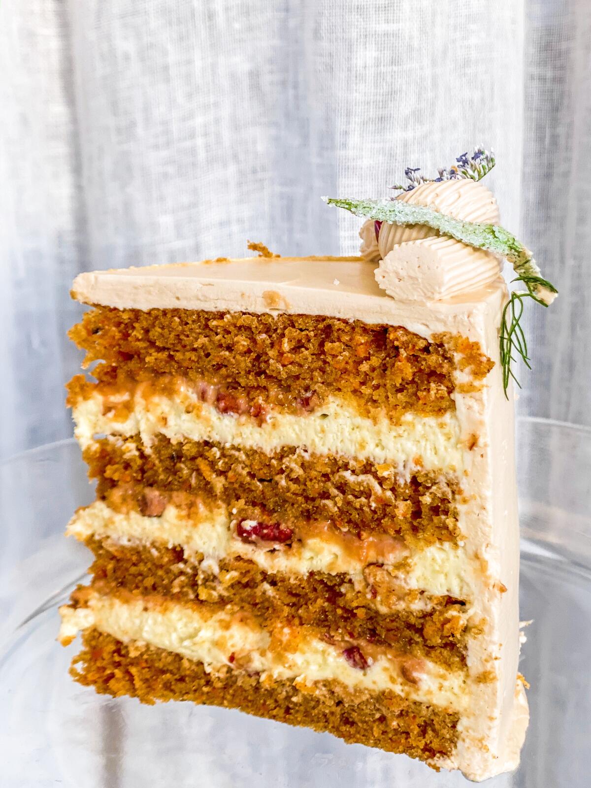 A slice of carrot cake with four layers of cake and icing