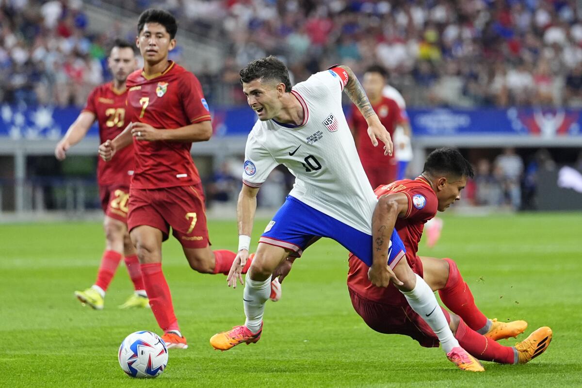 U.S. forward Christian Pulisic is grabbed by Bolivia's Hector Cuellar as they chase the ball.