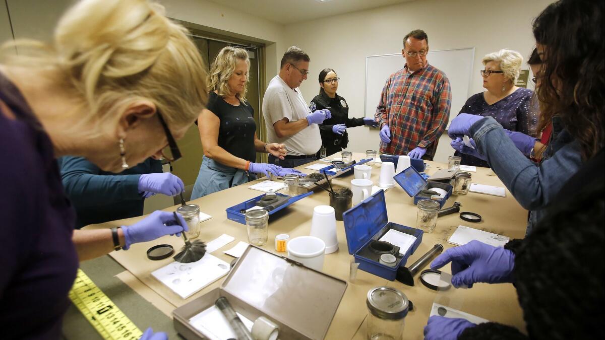 Uniformed instructor Krystal Aleman, center, tells participants in the Costa Mesa Citizens' Police Academy how investigators collect fingerprints from a crime scene.
