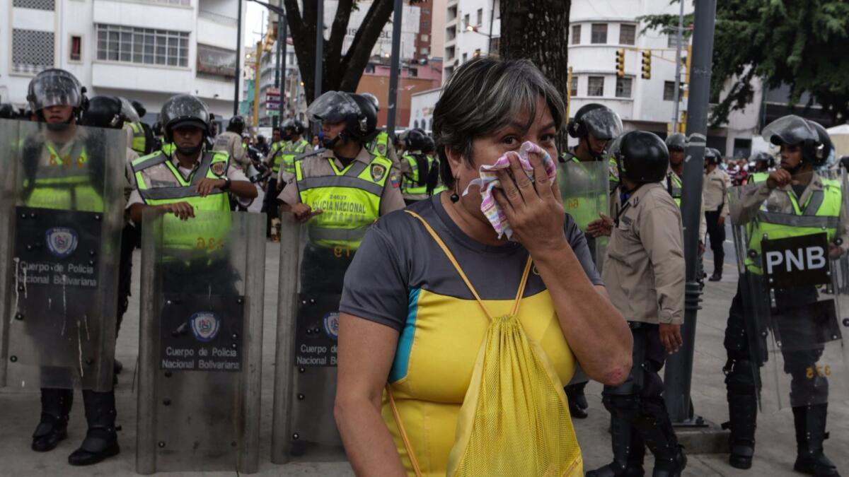 A woman protects herself from tear gas during protest in Caracas, Venezuela, on Friday. Several protests broke out after a Supreme Court ruling took power from congress raising fear of a dictatorship.