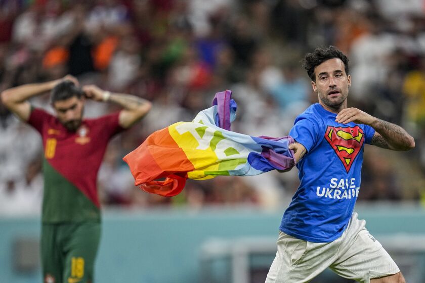 Un aficionado irrumpe en la cancha con la bandera arcoíris durante el partido del Grupo H entre Portugal y Uruguay, el lunes 28 de noviembre de 2022, en Lusail, Qatar. (AP Foto/Abbie Parr)