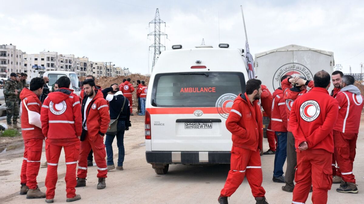 Syrian Red Crescent paramedics wait on a highway in eastern Aleppo for buses evacuating civilians from the government-held villages of Fuaa and Kafraya on April 14.
