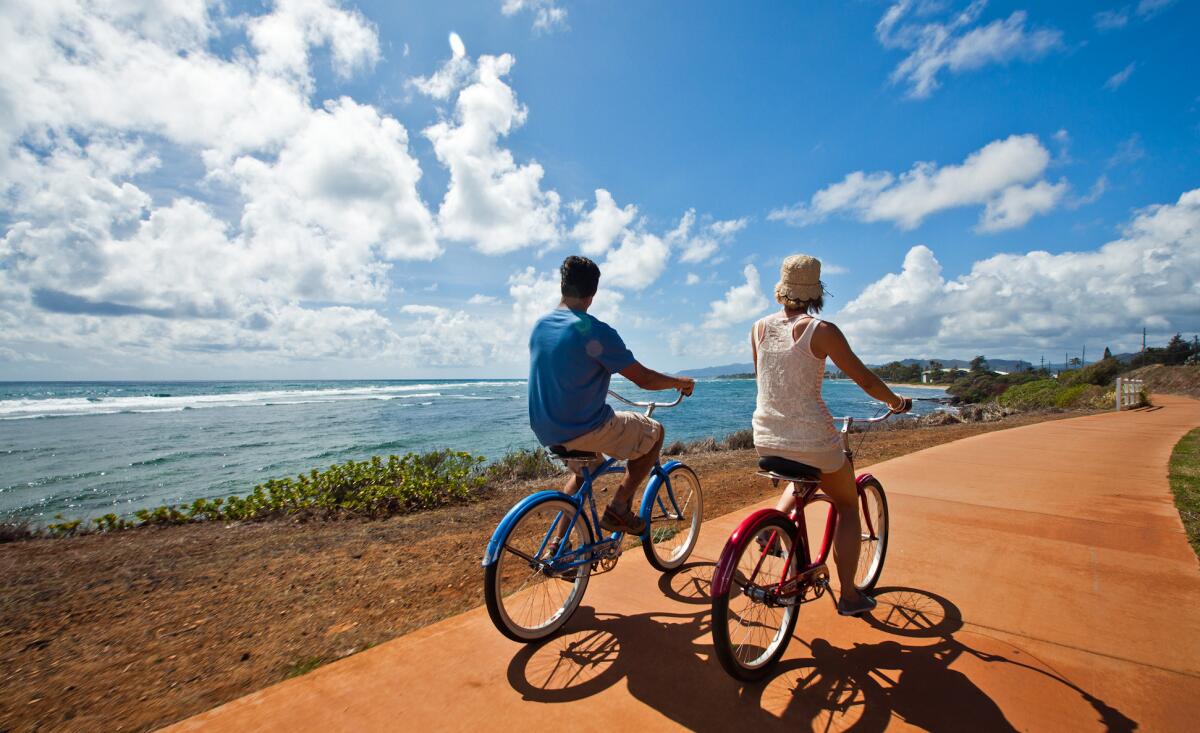 Cyclists enjoy a ride along the ocean in Kapaa on the island of Kauai. The Kauai Sands Hotel is offering a free car and free breakfast through Dec. 24.