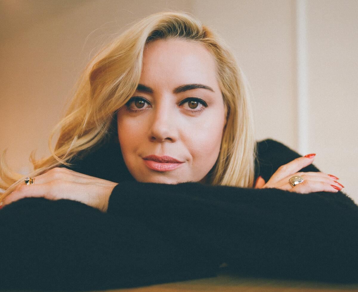 A blond woman rests her head on her crossed arms.