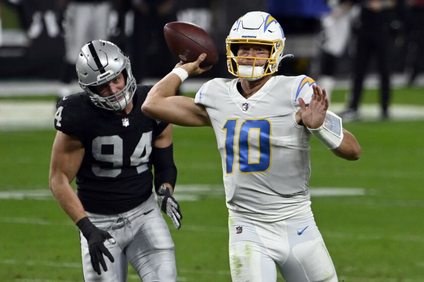 Chargers quarterback Justin Herbert looks to pass under pressure from Raiders defensive end Carl Nassib on Dec. 17, 2020.