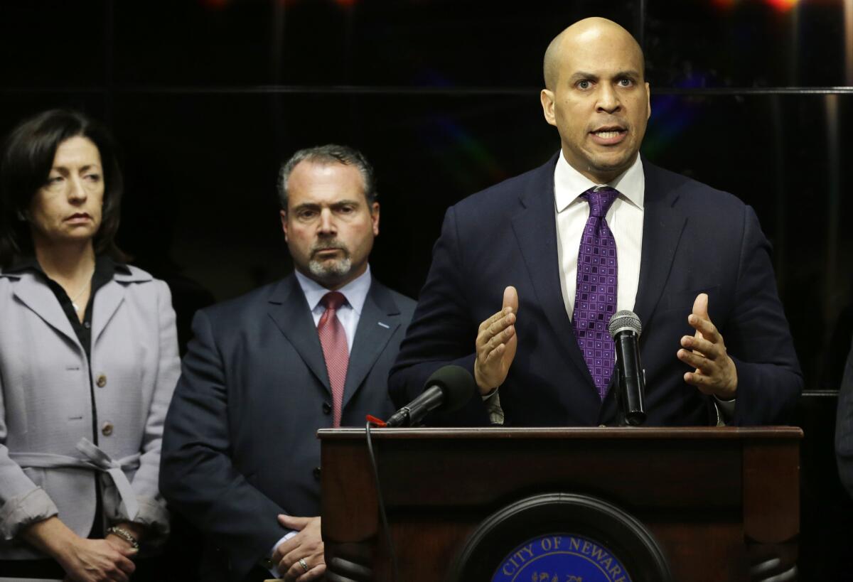 Newark Mayor Cory Booker responds angrily at a news conference regarding a video showing a naked young man being whipped because of his father's debt.