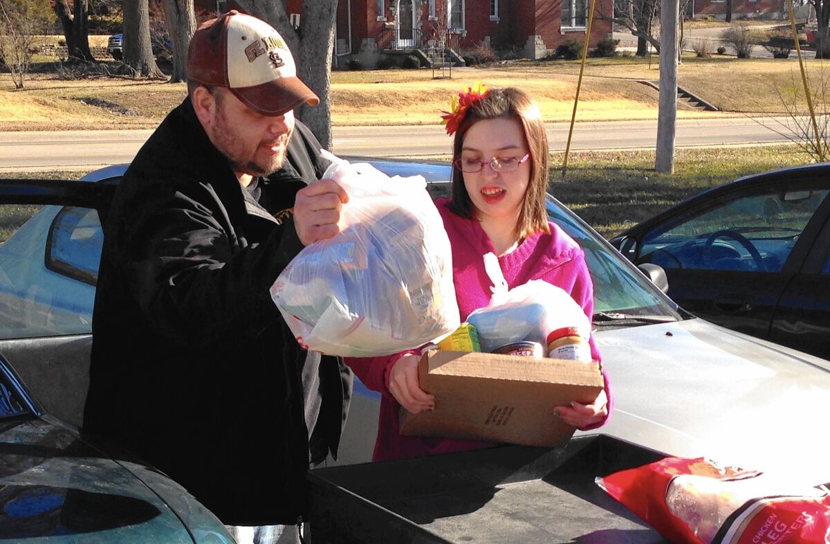Joe Heflin and a volunteer load groceries into his car at the Samaritan Center food pantry in Jefferson City, Mo. Heflin, 33, also receives food stamps but could lose them if he doesn’t meet newly enforced work requirements.
