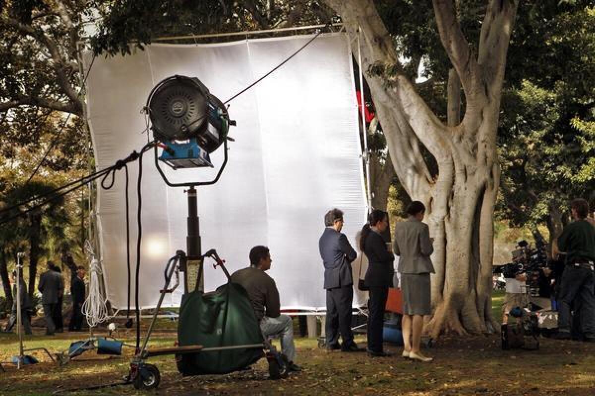 A film crew sets up lights and cameras on the lawn of Los Angeles City Hall. Rising employment in the motion picture and sound recording segment is helping to improve the county's job situation.