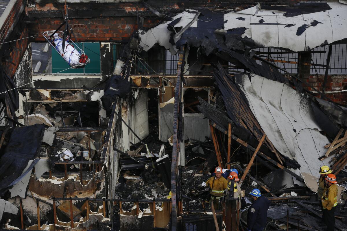 A body is lowered via cable from a charred building in the Westlake neighborhood.