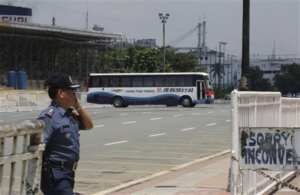 A tourist bus with some 25 people on board sits parked in front of the Quirino Grandstand during a hostage standoff at Rizal Park Monday, Aug. 23, 2010 in Manila, Philippines. Senior Police Inspector Rolando Mendoza, a dismissed policeman armed with automatic rifle, seized the bus in Manila Monday with 25 people aboard, mostly Hong Kong tourists in a bid to demand reinstatement, police said. (AP Photo/Bullit Marquez)