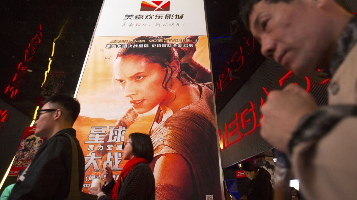 People walk past a poster for Disney’s “Star Wars” film at a movie theater in Beijing on Jan. 9.