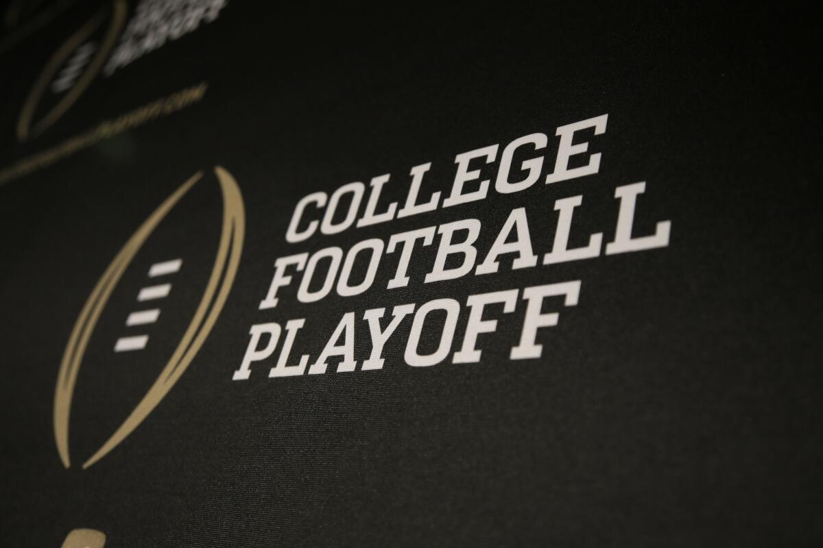 FILE - The College Football Playoff logo is printed across a backdrop during a news conference.