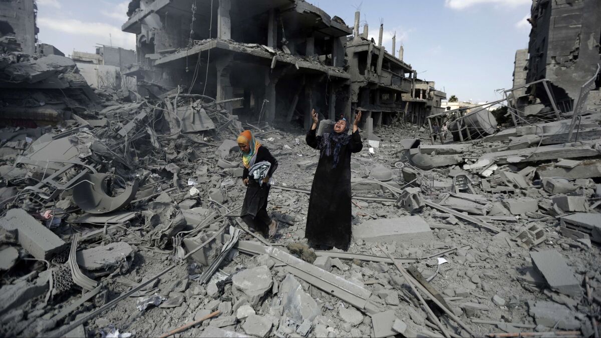Palestinians are surrounded by destruction in the northern district of Beit Hanoun in the Gaza Strip on July 26, 2014.