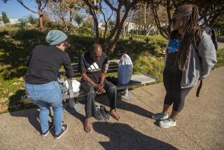 SANTA MONICA, CA-JANUARY 26,2024:Devon O'Malley, left, a harm reduction case manager with the Venice Family Clinic, and Chelsea Agee, a prevention advocate with the Venice Family Clinic, talk with Ken Newark, 63, who is homeless, at Tongva Park in Santa Monica. O'Malley handed him underwear, socks, and a Narcon nasal kit. (Mel Melcon / Los Angeles Times)