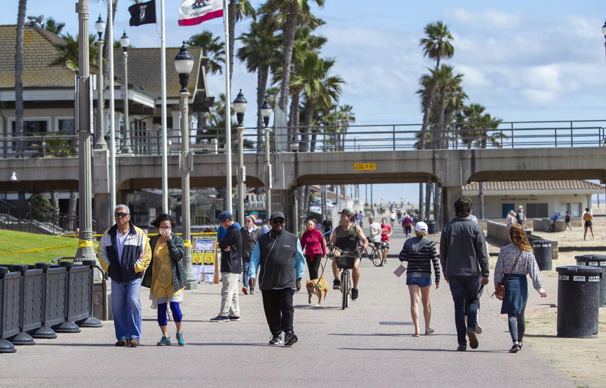 People walk along the path near the closed Huntington Beach Pier last week.