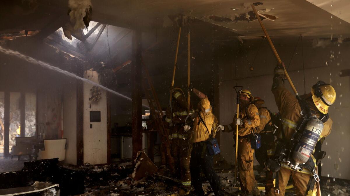 Firefighters work in a Linda Flora Drive home scorched by the Skirball fire in Bel-Air.