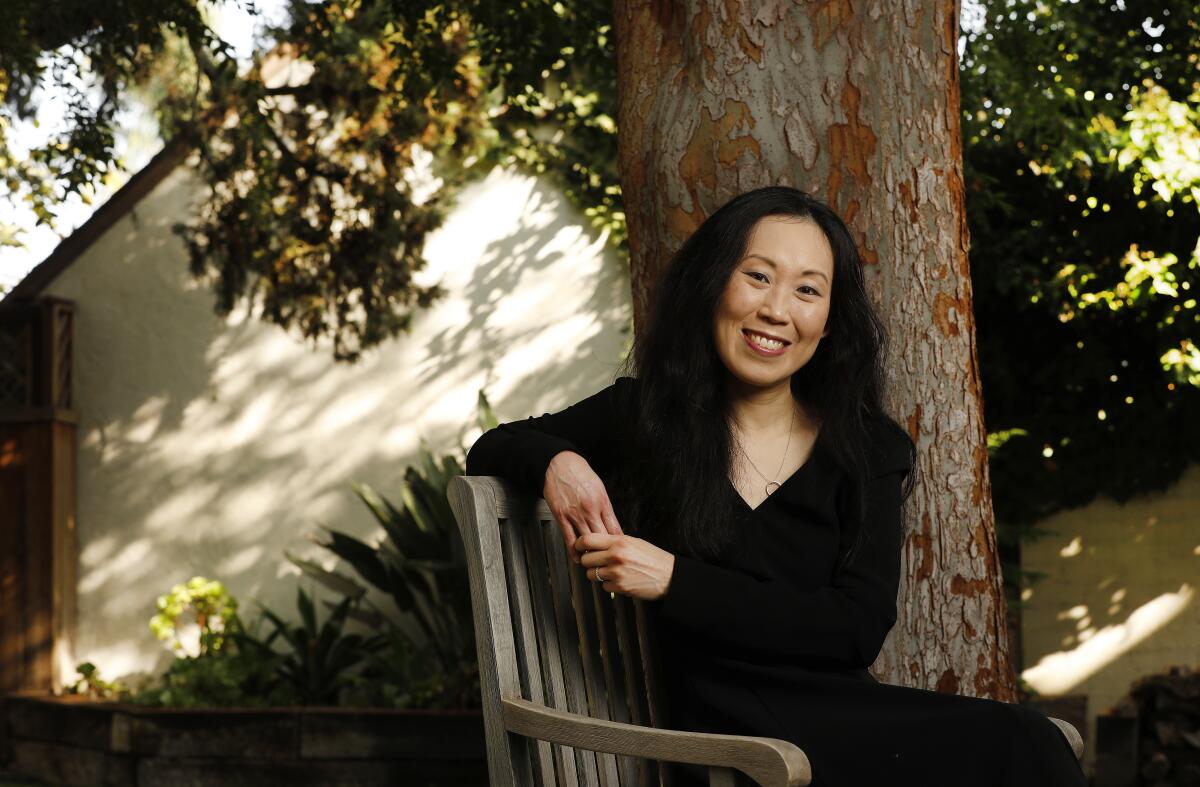A woman wearing all black sits in a chair underneath a tree.
