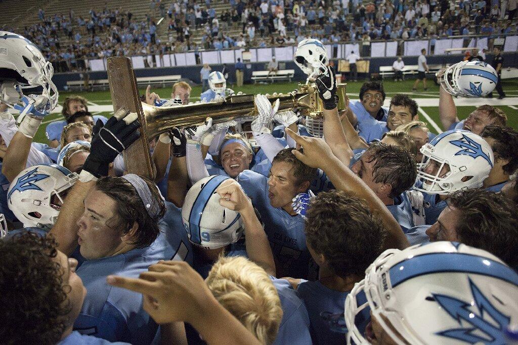 Corona del Mar High football players celebrate after defeating Newport Harbor, 24-3, in the Battle of the Bay at Orange Coast College Thursday night.