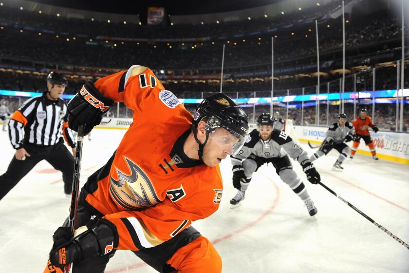 The Ducks' Saku Koivu retrieves the puck in the corner as the Kings' Jarret Stoll comes in for the check at Dodger Stadium back in January.