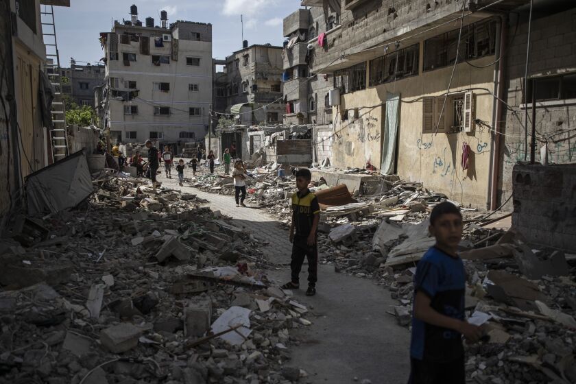 Palestinian children walk next to rubble from a house was that was hit by early morning Israeli airstrikes, in Gaza City, Monday, May 17, 2021. (AP Photo/Khalil Hamra)