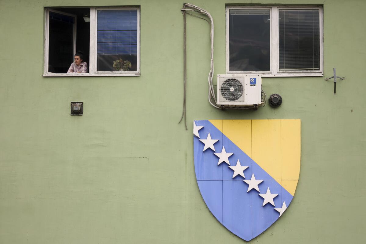 A woman looks through the window next to the giant flag of Bosnia and Herzegovina in Sarajevo, Bosnia.