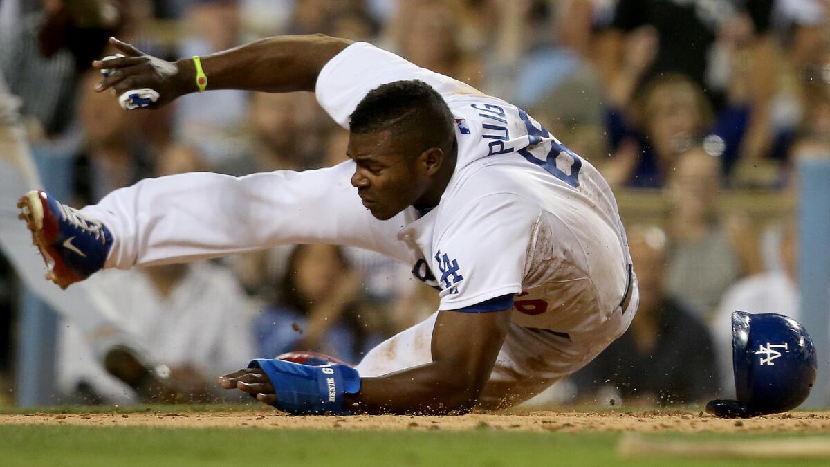 Dodgers center fielder Yasiel Puig tumbles past San Diego Padres catcher Yasmani Grandal (not pictured) to score a run in the third inning of the Dodgers' 4-1 loss Wednesday.