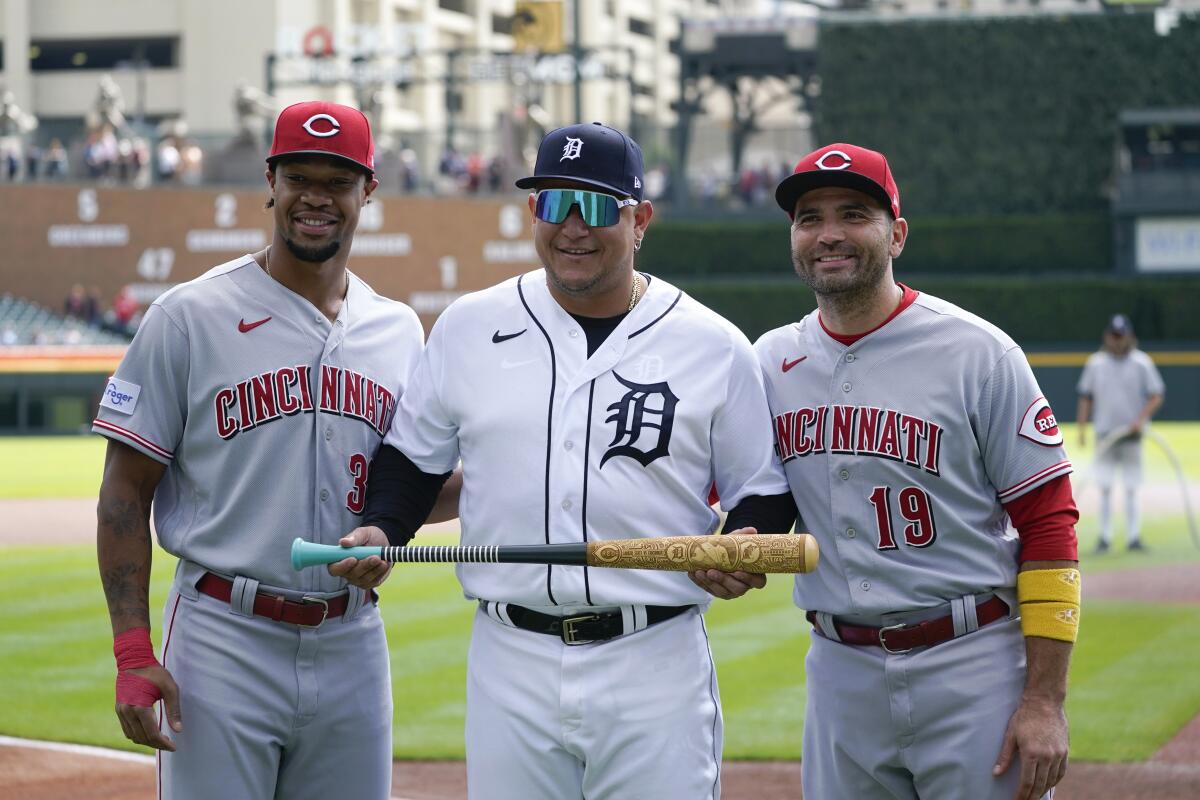 Cincinnati Reds' Will Benson, left, and Joey Votto present Miguel Cabrera a bat in honor of his upcoming retirement.