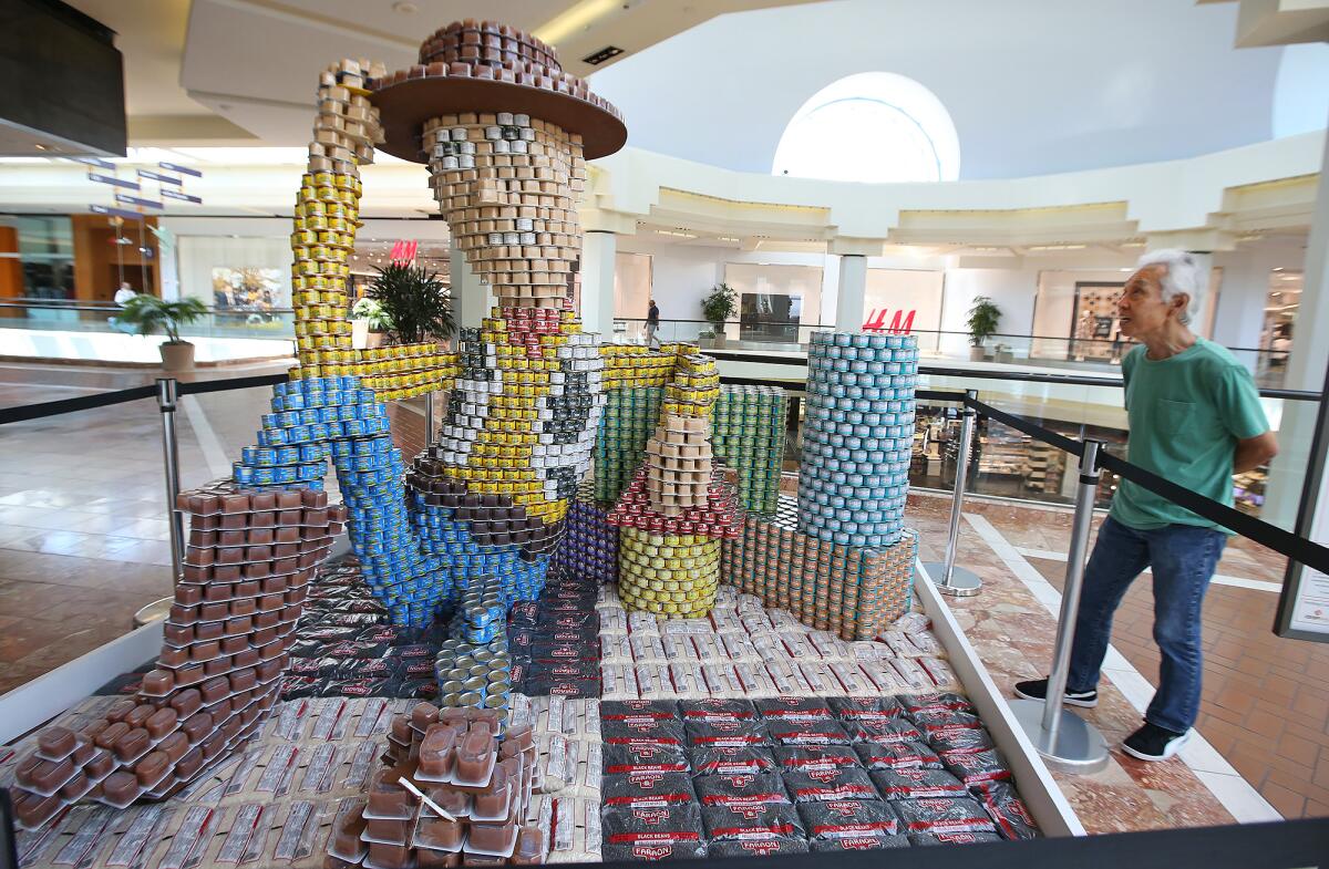 Woody from "Toy Story," built of 7,000 cans of food, gets the attention of shopper Tony Moniz at South Coast Plaza in Costa Mesa on Wednesday. The creation, titled "There's a can in my boot," is part of Canstruction Orange County to benefit the Orange County Food Bank. The display was built by a Disneyland Resort team.