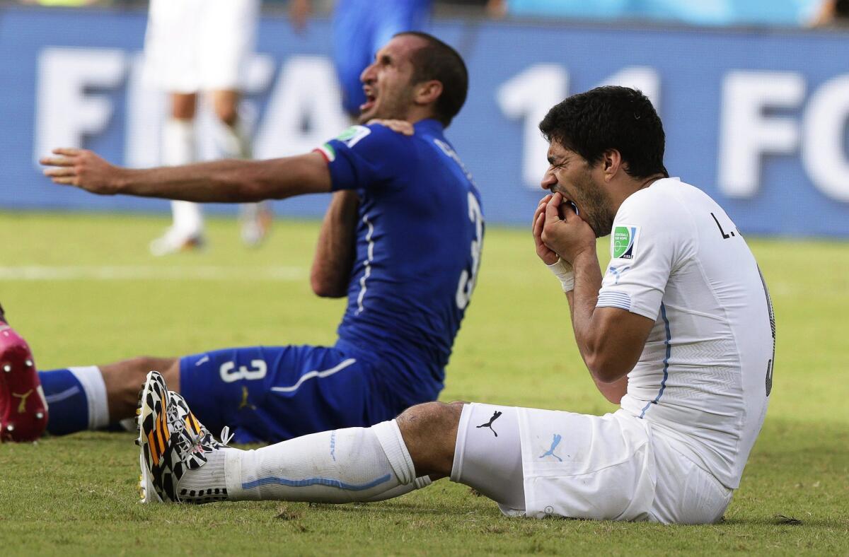 Italy's Giorgio Chiellini, left, claims he was bitten by Uruguay's Luis Suarez during a World Cup Group D preliminary round match Tuesday at the Estadio Arena das Dunas in Natal, Brazil.