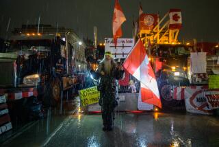 A demonstrator gestures as he stands before trucks during a protest by truck drivers over pandemic health rules and the Trudeau government, outside the parliament of Canada in Ottawa on February 11, 2022. - Canada's Ontario province Friday declared a state of emergency over the trucker-led protests paralyzing the capital and blocking trade with the United States, Premier Doug Ford announced. (Photo by Ed JONES / AFP) (Photo by ED JONES/AFP via Getty Images)