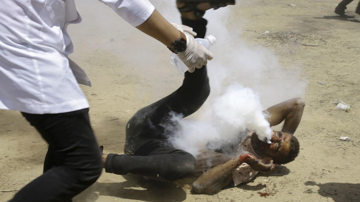 A Palestinian medic rushes to help a protester who was shot in the face with a tear gas canister fired by Israeli troops near the Gaza Strip's border with Israel, east of Khan Yunis, on Friday.