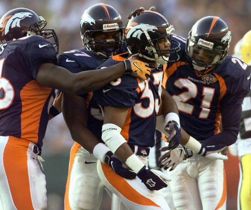 FILE - In this file photo dated Sunday, Jan. 25, 1998, Denver Broncos Dedrick Dodge (33) celebrates with teammates Randy Hilliard (21) and Anthony Lynn (37) after he stopped Green Bay Packers' Antonio Freeman on a kickoff return in the second quarter of Super Bowl XXXII, at San Diego's Qualcomm Stadium. The year 2021 marks the 30th anniversary of the World League of American Football, and Dedrick Dodge joined the London Monarchs and helped them win the first World Bowl in 1991. (AP Photo/Susan Ragan, FILE)
