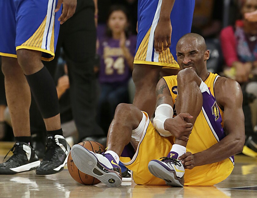 Kobe Bryant grimaces and grabs his leg on the basketball court.