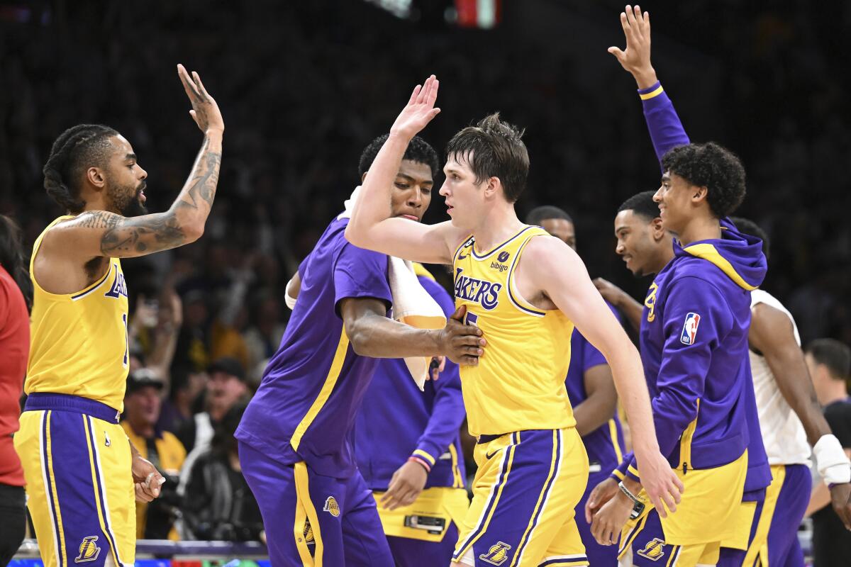 Lakers guard Austin Reaves, right, high-fives teammate D'Angelo Russell as he receives a pat on the chest from Rui Hachimura.