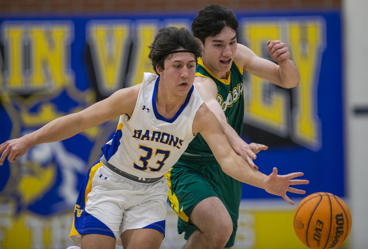 Fountain Valley's Troy Leach, left, and Edison's Kaz Hampton battle for a ball during a Surf League game on Thursday.