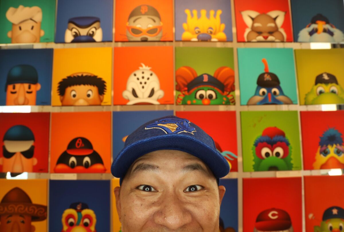 S. Preston, a sports "minimalist" artist, mimics the faces of his "Minimalist MLB Mascot" series at his studio on the Anaheim Garden Walk. Preston has contracts with several pro sports organizations who buy his art.