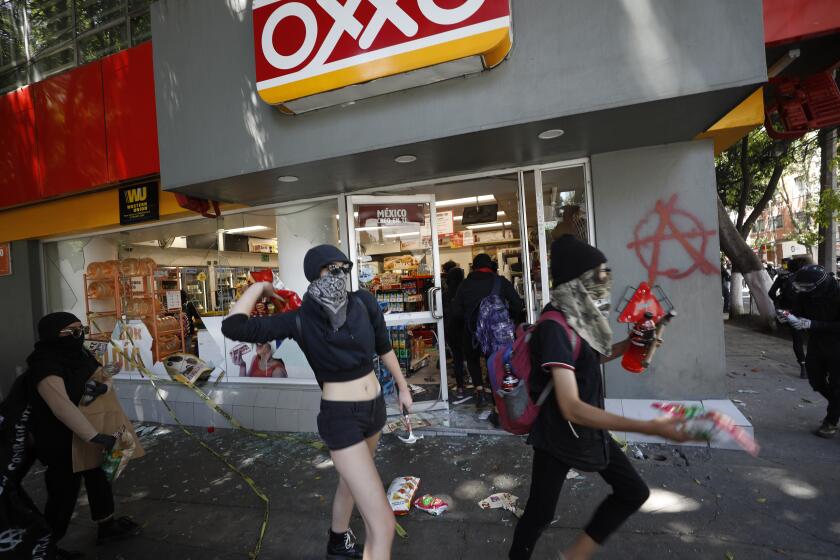 Anarchist protesters loot a convenience store before going to attack a security barrier around the nearby U.S. Embassy, in Mexico City, Friday, June 5, 2020. Following the recent deaths of George Floyd and Giovanni Lopez after encounters with U.S. and Mexican police, anarchist protesters who are known for their violent tactics attacked a barrier outside the U.S. Embassy, smashed store fronts and looted convenience stores, before clashing with police in an upscale neighborhood.(AP Photo/Rebecca Blackwell)